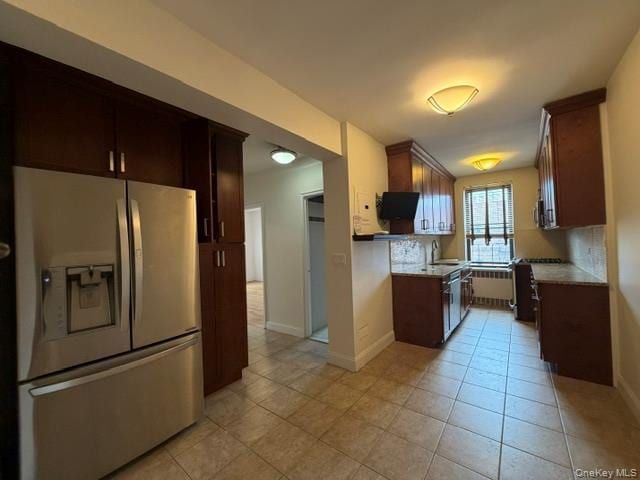Kitchen featuring dark wood-finish cabinetry, stainless steel French door refrigerator, tiled flooring, built-in lighting, and stone-finish countertops