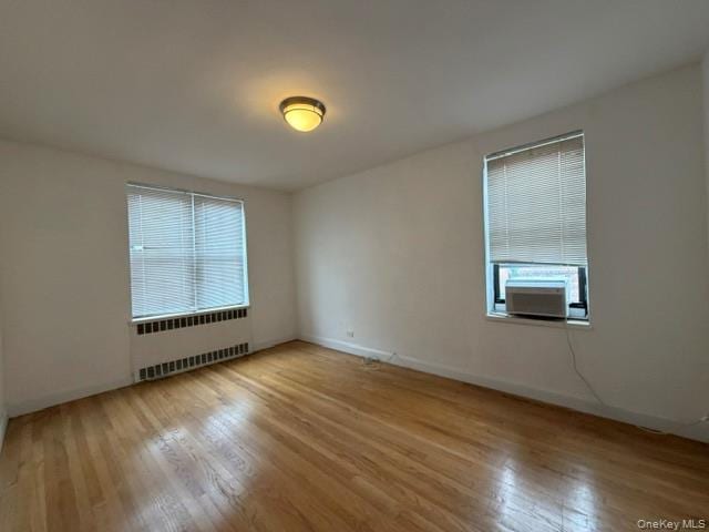 Hardwood flooring, window-mounted air conditioning unit, ceiling-mounted light fixture, and horizontal blinds
