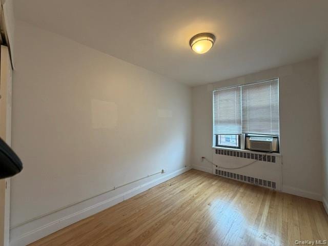 Wood-finish flooring, white walls, and a window with blinds