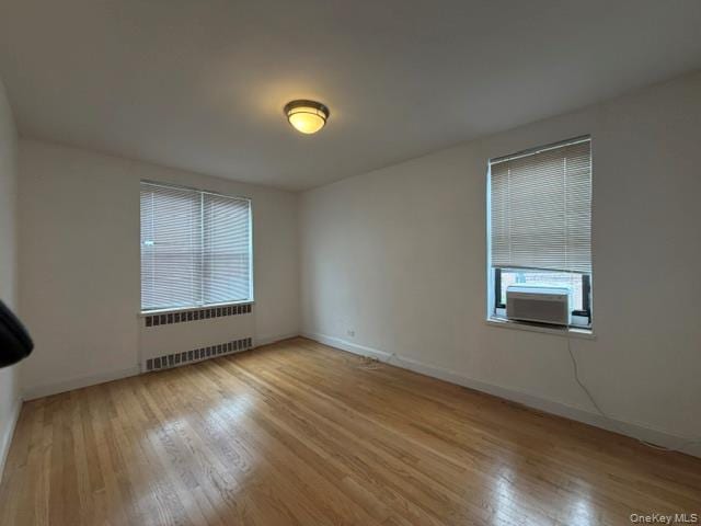 Hardwood flooring, painted walls, window with blinds, ceiling-mounted light fixture, and window-mounted air conditioning unit