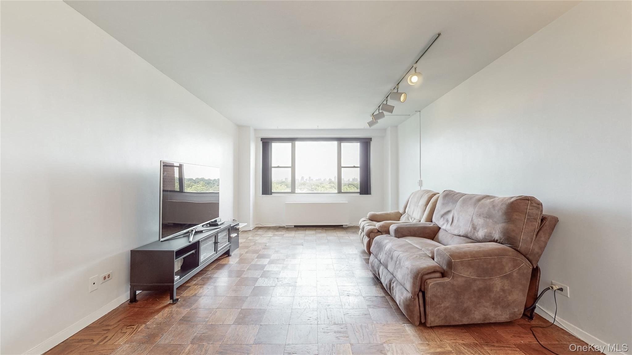 Wood-finish parquet flooring throughout, expansive white walls, track lighting fixture, and large windows