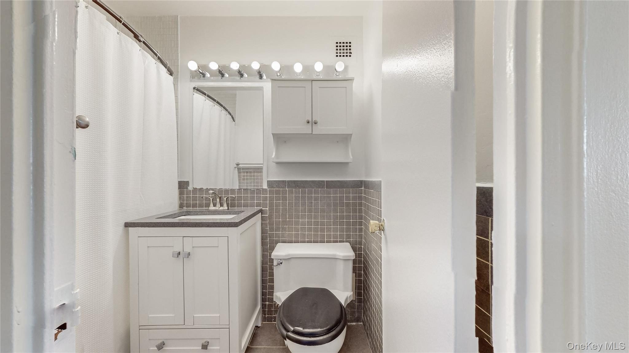 White vanity with under-sink storage, a single basin sink, and a dark-toned countertop