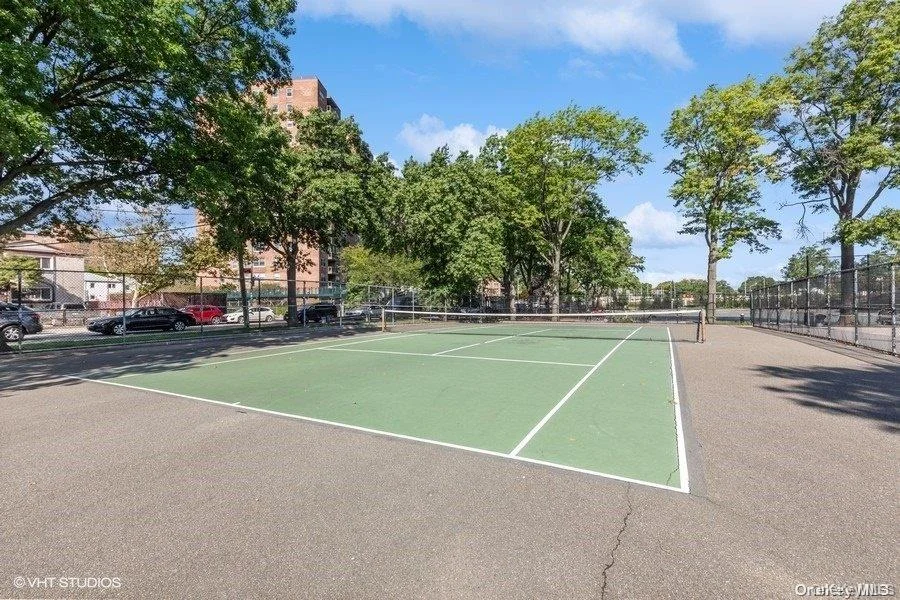 Outdoor tennis court with green playing surface and white line markings