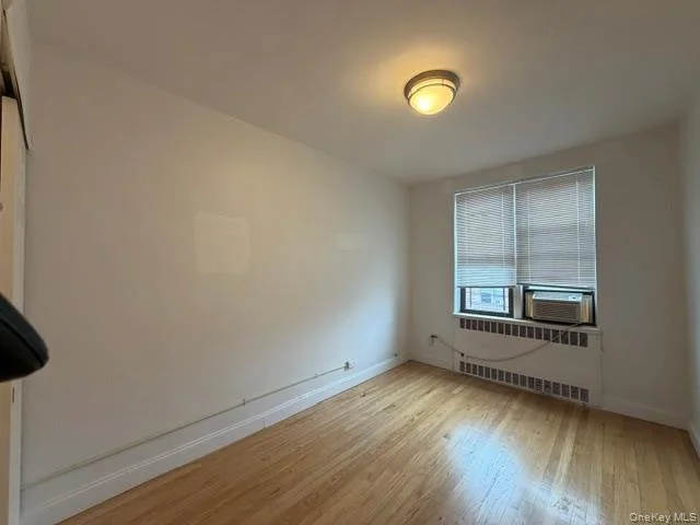 Wood-finish flooring, white walls, and a window with blinds